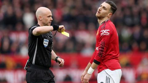 Referee Anthony Taylor shows a yellow card to Diogo Dalo